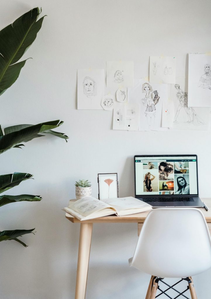 Kreativer Arbeitsplatz mit Laptop und Zeichnungen – Sinnbild für persönlichen Fortschritt und individuelle Reha-Ziele.