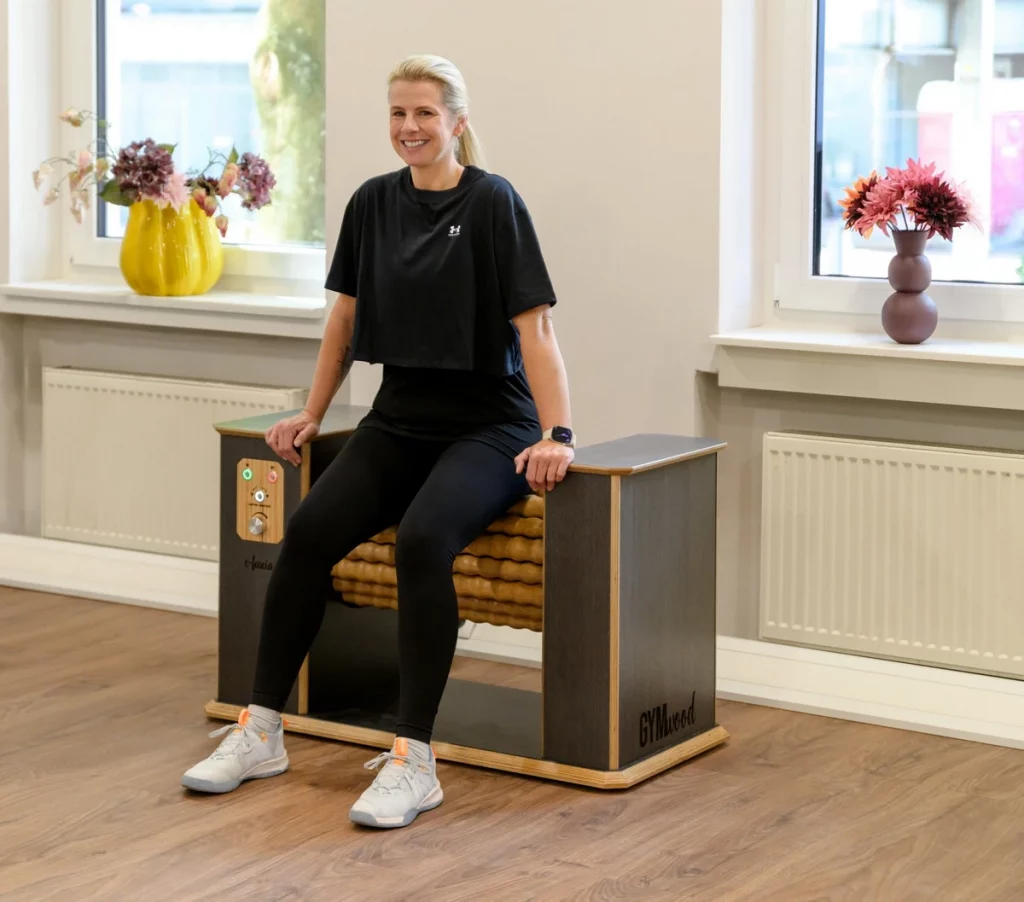 Frau nutzt das Gymwood-Massagegerät bei PhysioPunkt Brühl zur Entspannung und Regeneration