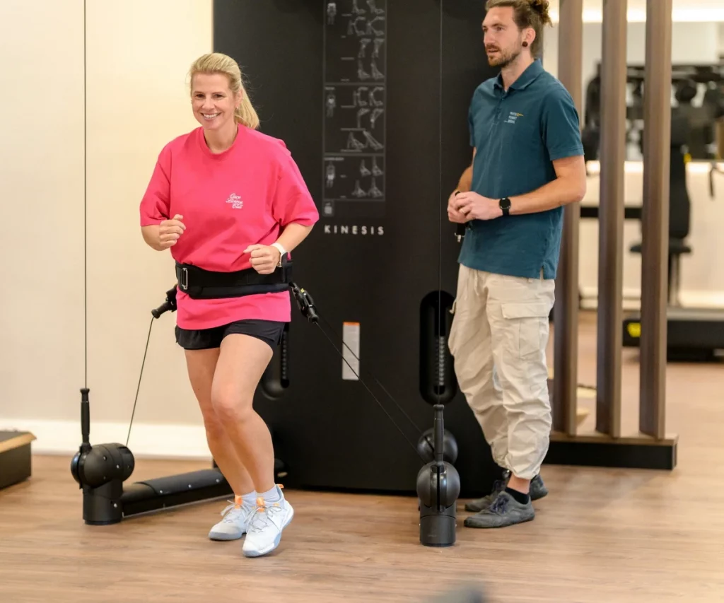 Patientin trainiert an der Kinesis One bei PhysioPunkt Brühl, begleitet durch einen Physioherapeuten