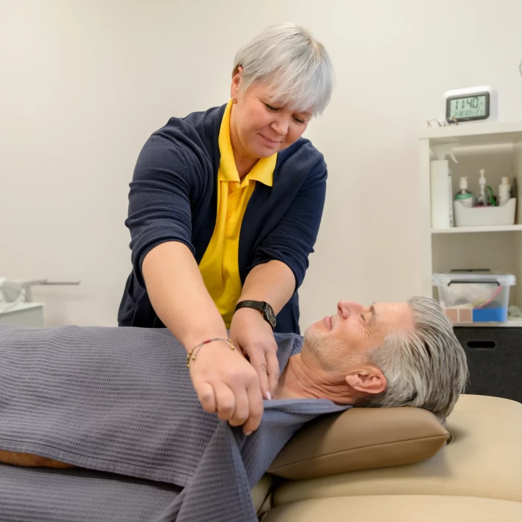 Physiotherapeutin von Physiopunkt Brühl legt eine wohltuende Fango-Wärmeanwendung bei einem Patienten an
