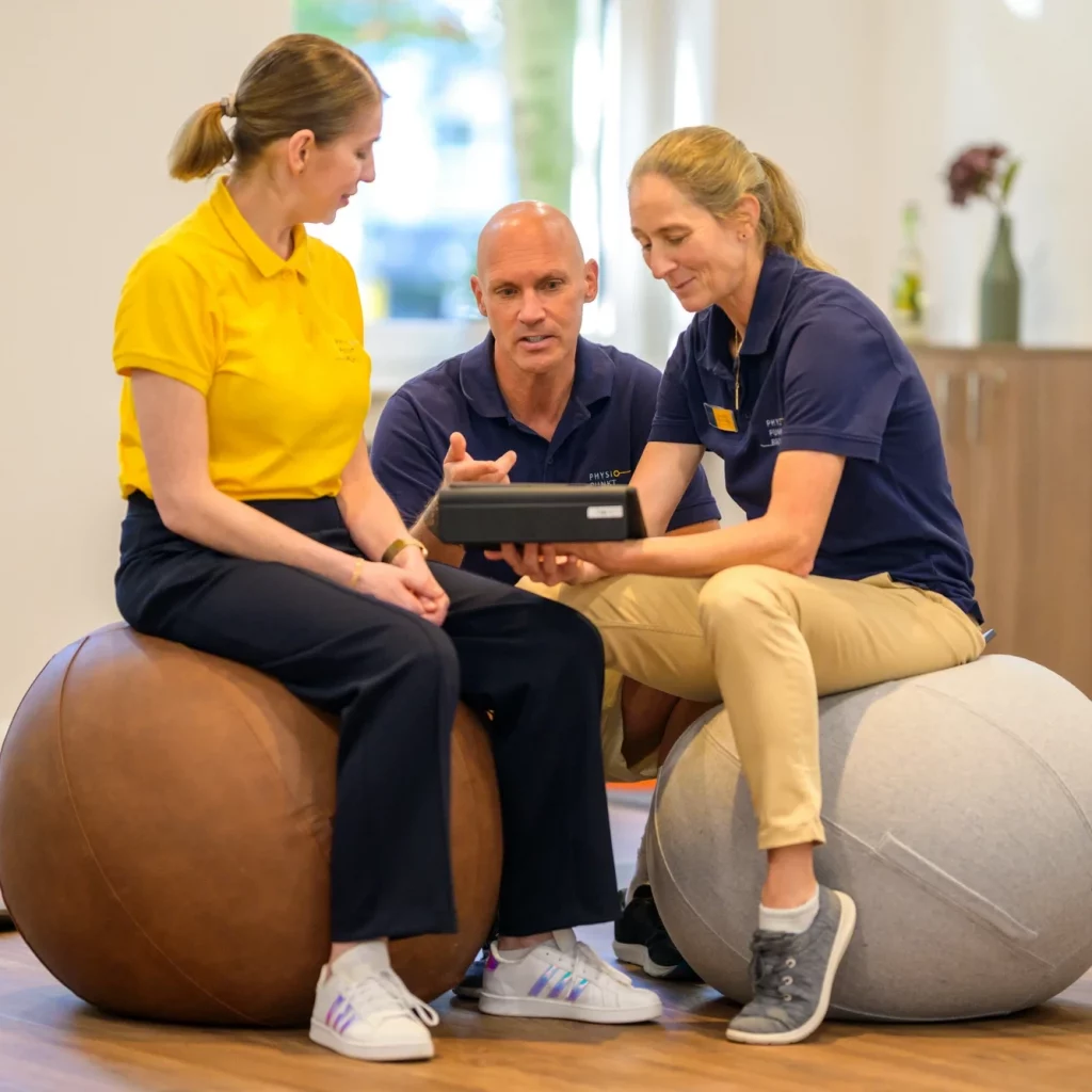 Therapeutenteam von Physiopunkt Brühl bei einer Besprechung auf Therapiebällen im Trainingsbereich