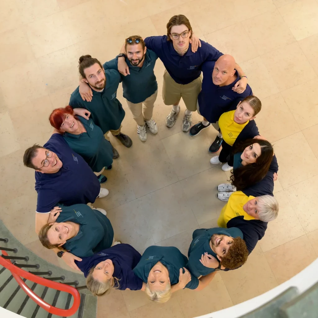 Das Team von Physiopunkt Brühl steht im Kreis zusammen und blickt lächelnd nach oben – Symbol für Zusammenhalt und Gemeinschaft